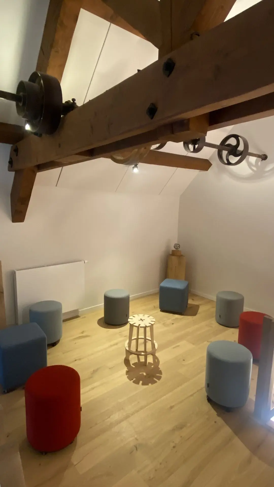 Le cercle de poufs sous les poutres anciennes, prêt pour les ateliers